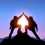 The Silhouette of two man with success gesture standing on the top of mountain